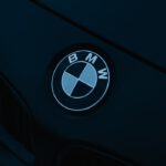 A stylish close-up of BMW logo on a sleek car hood in low lighting.