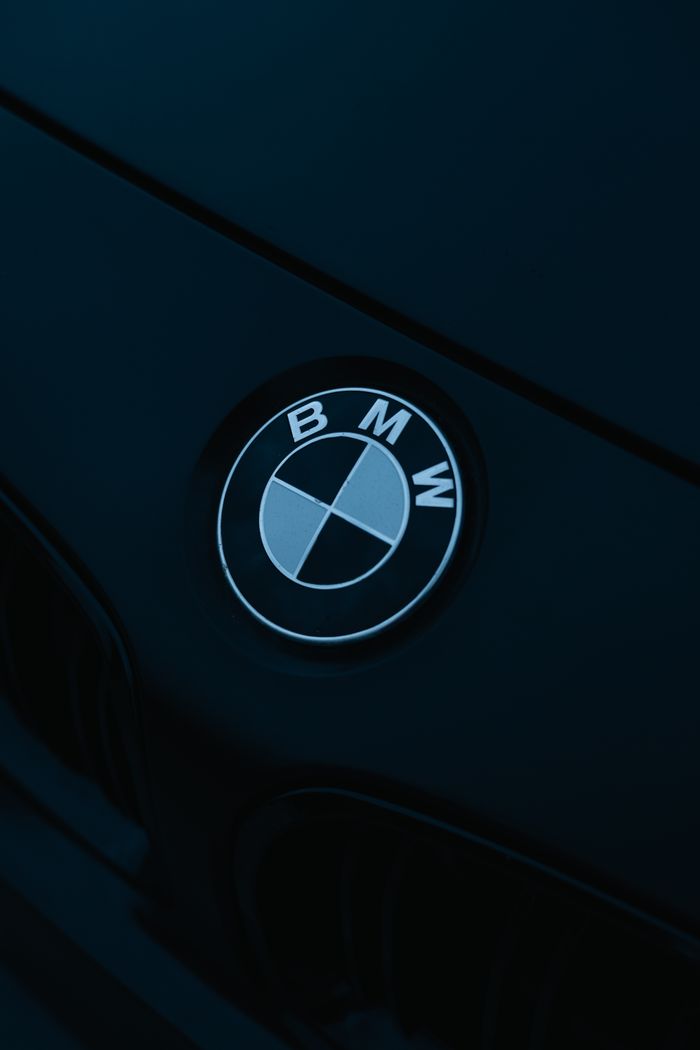 A stylish close-up of BMW logo on a sleek car hood in low lighting.